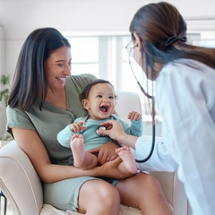 Doctor using a stethoscope to check a young patient's heart.