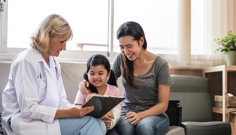 Pediatrician showing information on digital tablet to mother of child