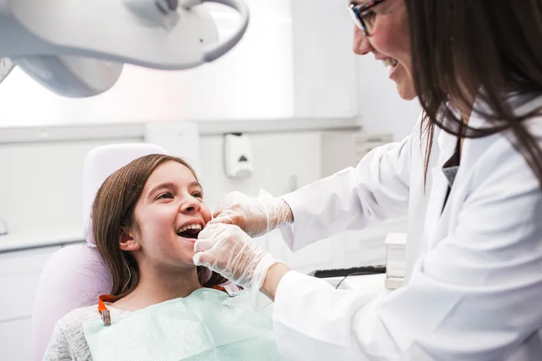 Young Girl Getting Her Teeth Flossed