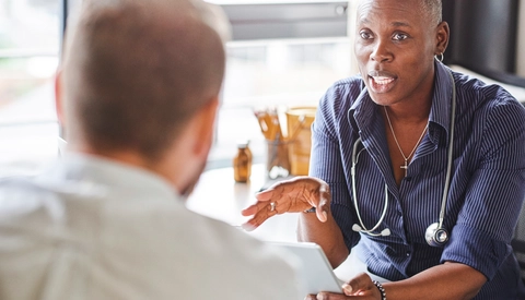 Doctor Holds Digital Tablet While Talking to Patient