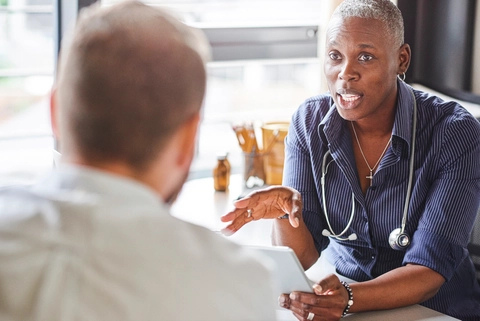 Doctor Holds Digital Tablet While Talking to Patient