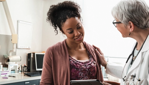 Gynecologist with digital tablet comforting pregnant patient