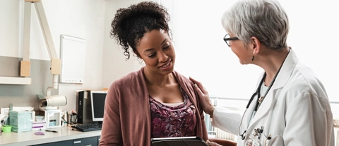Gynecologist with digital tablet comforting pregnant patient