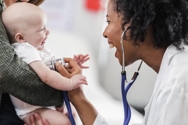 Female Doctor Laughing While Examining Baby
