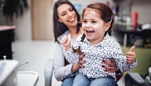 Child Laughing While Being Held By Family Member in Medical Setting
